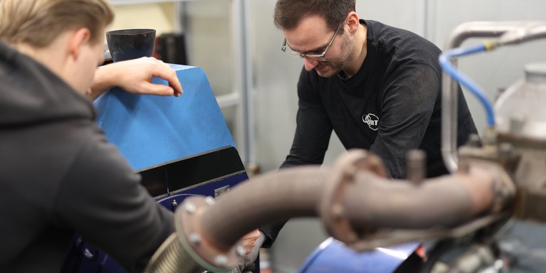 Zwei Studenten arbeiten an einer großen Maschine.