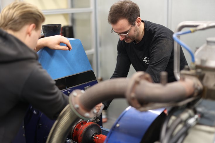Zwei Studenten arbeiten an einer großen Maschine.