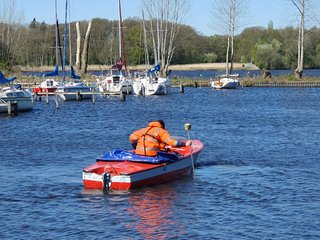 Studierende messen Wassertiefe mit Lotstab und GNSS aus Boot heraus