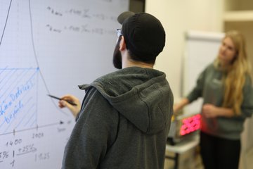 Student zeichnet löst eine mathematische Gleichung am Smartboard.