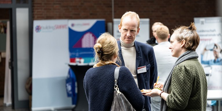 Drei Personen unterhalten sich auf einer Veranstaltung.