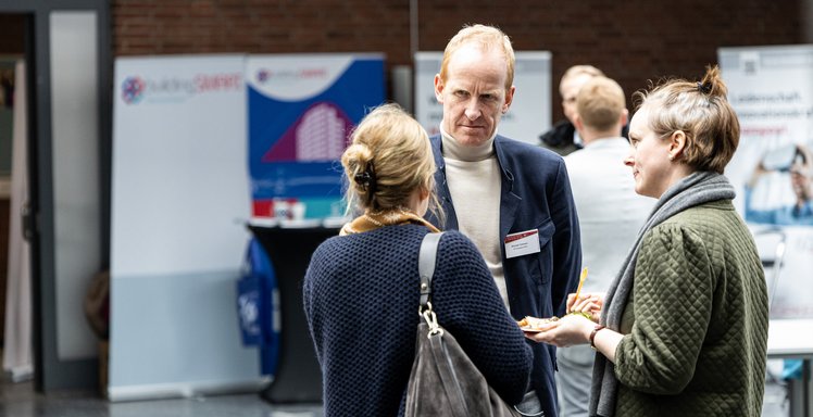 Drei Personen unterhalten sich auf einer Veranstaltung.