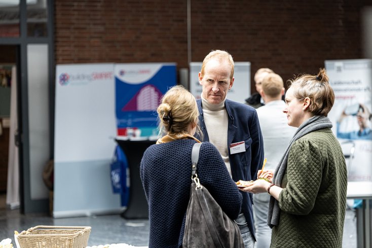Drei Personen unterhalten sich auf einer Veranstaltung.