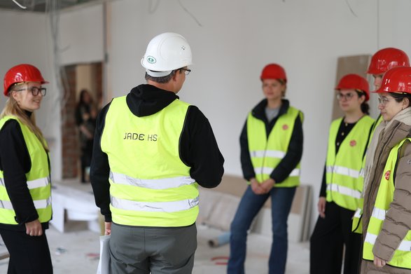 Dozent erklärt Studierenden etwas auf der Baustelle.