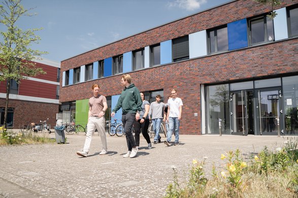 Studierende laufen vor dem Campusgebäude