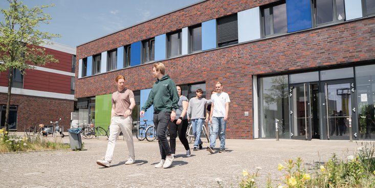 Studierende laufen vor dem Campusgebäude