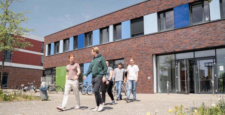 Studierende laufen vor dem Campusgebäude