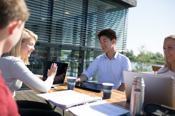 Studierende sitzen an einem Tisch vor der Mensa