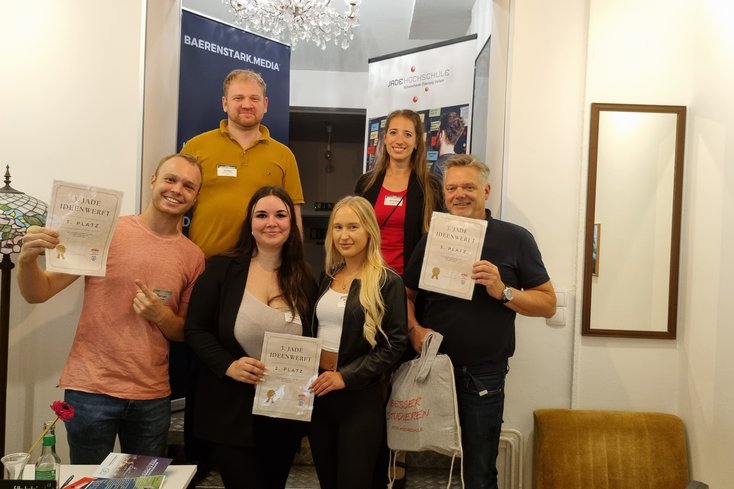Zu den glücklichen Gewinner_innen der dritten Jade Ideenwerft zählten (unten v.l.n.r.) Florian mit seinem nachhaltigen Start-Up "ancol", Romina und Kira mit ihrer Tourismus-App "Roki Travel" und Frank mit seiner Karriereberatung "Coachinglabor". Die Preise überreichten Julian Fuchs (Baerenstark Media) und Annika Schöbel (Jade HS). (Foto: Daniela Wrage/Jade HS)
