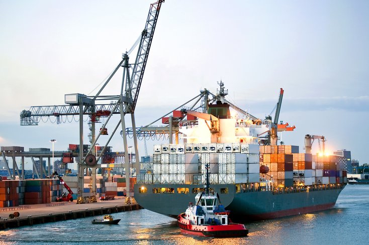 Großes Containerschiff und ein Schlepper in einem Hafen