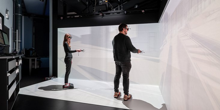 Zwei Personen, die mit VR-Brillen und Kontrollern ausgestattet sind, arbeiten im Labor für digitales Engineering.