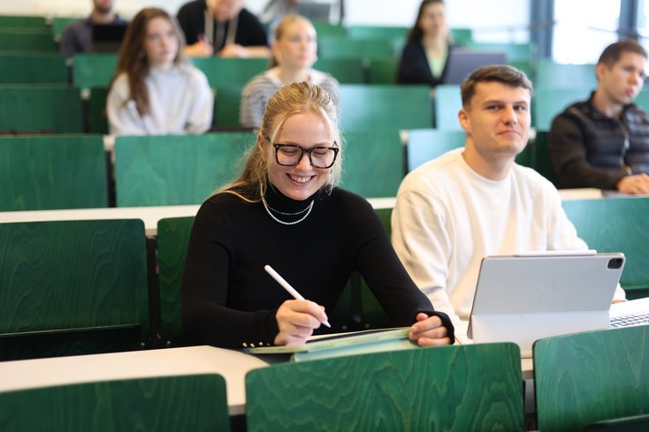 Studierende sitzen im Vorlesungssaal und machen Notizen.