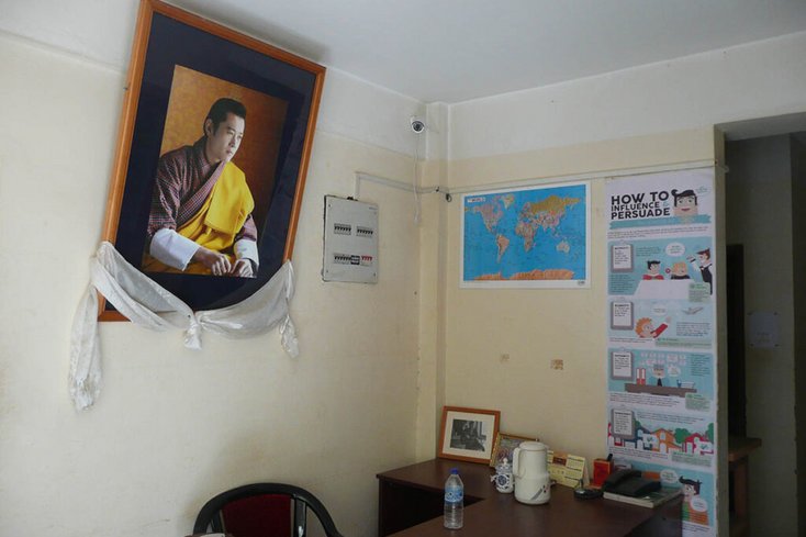 Ein Bild des Königs von Bhutan in einem Vorraum einer Redaktion. Der Seidenschal am Rahmen gleicht dem Kadak, einem Schal, der im bhuddistischen Umfeld häufig zum Abschied – zum Beispiel vor einer Reise – verschenkt wird.