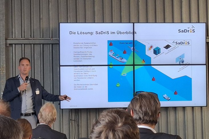 Prof. Dr.-Ing. Christian Denker stellt das Projekt „SaDris“ als 10-minütigen Fachvortrag im Hangar des Flugplatzes in Oldenburg-Hatten vor (Foto: Jade HS / Alexander Büchel)