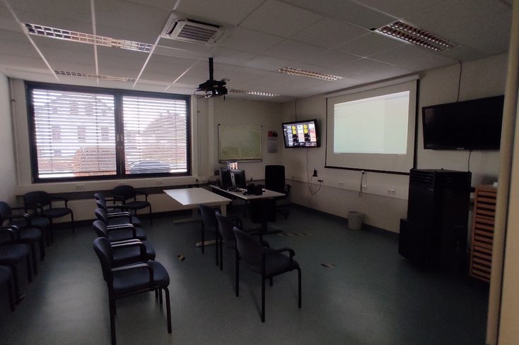 Raum mit mehreren Stühlen. An der Wand hängt ein Bildschirm.