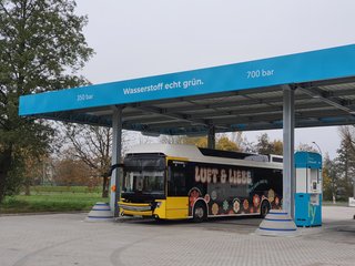 Ein Bus, der mit Wasserstoff fährt, steht unter einer Tankstelle.