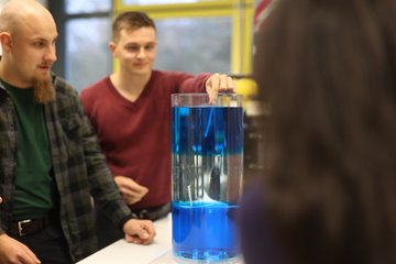 Zwei Studierende stehen um eine Wassersäule, einer hält einen Teststreifen hinein.