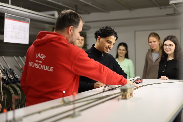 Dozent zeigt Versuch im Eisenbahnlabor.