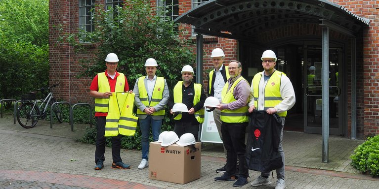 Prof. Dr. Sebastian Hollermann (IDoK/Jade HS (links)) sowie Firmenvertreter bei der Übergabe von Bauhelmen und Warnwesten (Foto: Jade HS)