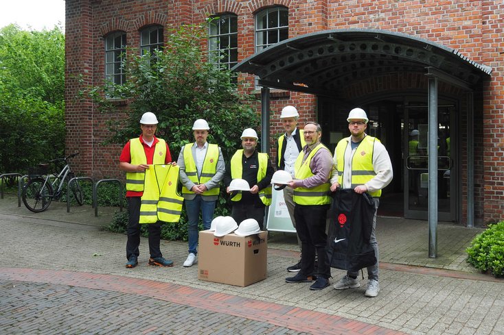 Prof. Dr. Sebastian Hollermann (IDoK/Jade HS (links)) sowie Firmenvertreter bei der Übergabe von Bauhelmen und Warnwesten (Foto: Jade HS)