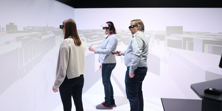 Drei Personen interagieren mit einem virtuellen Stadtmodell.