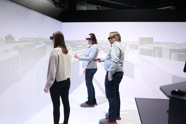 Drei Personen interagieren mit einem virtuellen Stadtmodell.