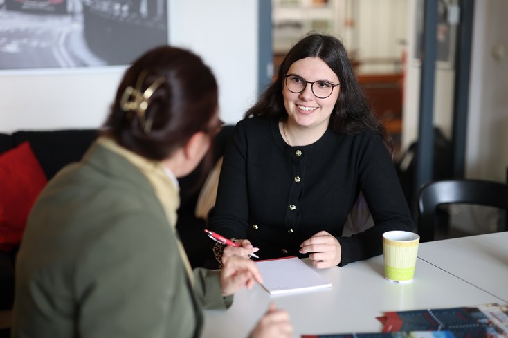 Studentin lächelt Dozentin an und macht sich Notizen.