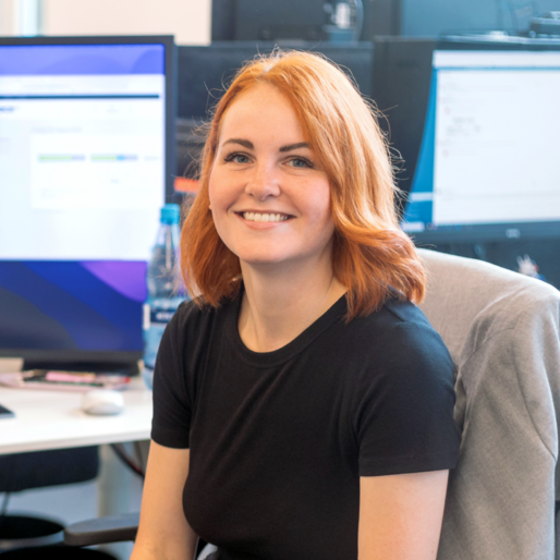 Junge Frau mit rotblonden Haaren im Porträt, sie lächelt in die Kamera.