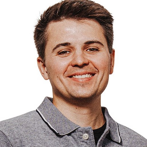 Portraitfoto eines jungen Mannes mit dunkelbraunen Haaren und grauem Poloshirt, er lächelt in die Kamera