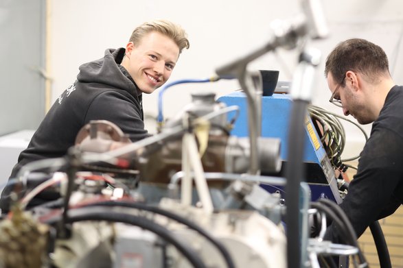 Zwei Studenten arbeiten an einer großen Maschine.