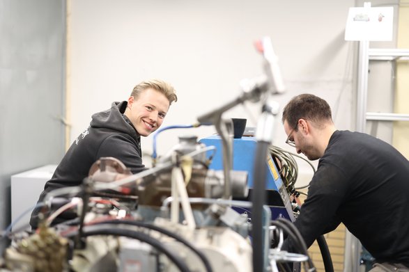 Zwei Studenten arbeiten an einer großen Maschine.