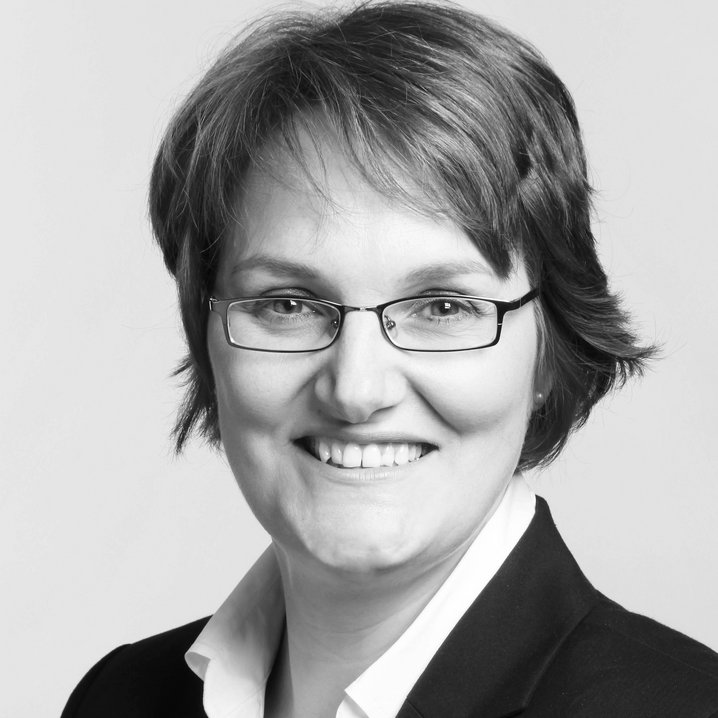 Porträtaufnahme einer Frau mit kurzen dunklen Haaren und Brille, die lächelt