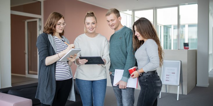 Eine Gruppe von vier jungen Menschen steht um einen Laptop und arbeitet zusammen.