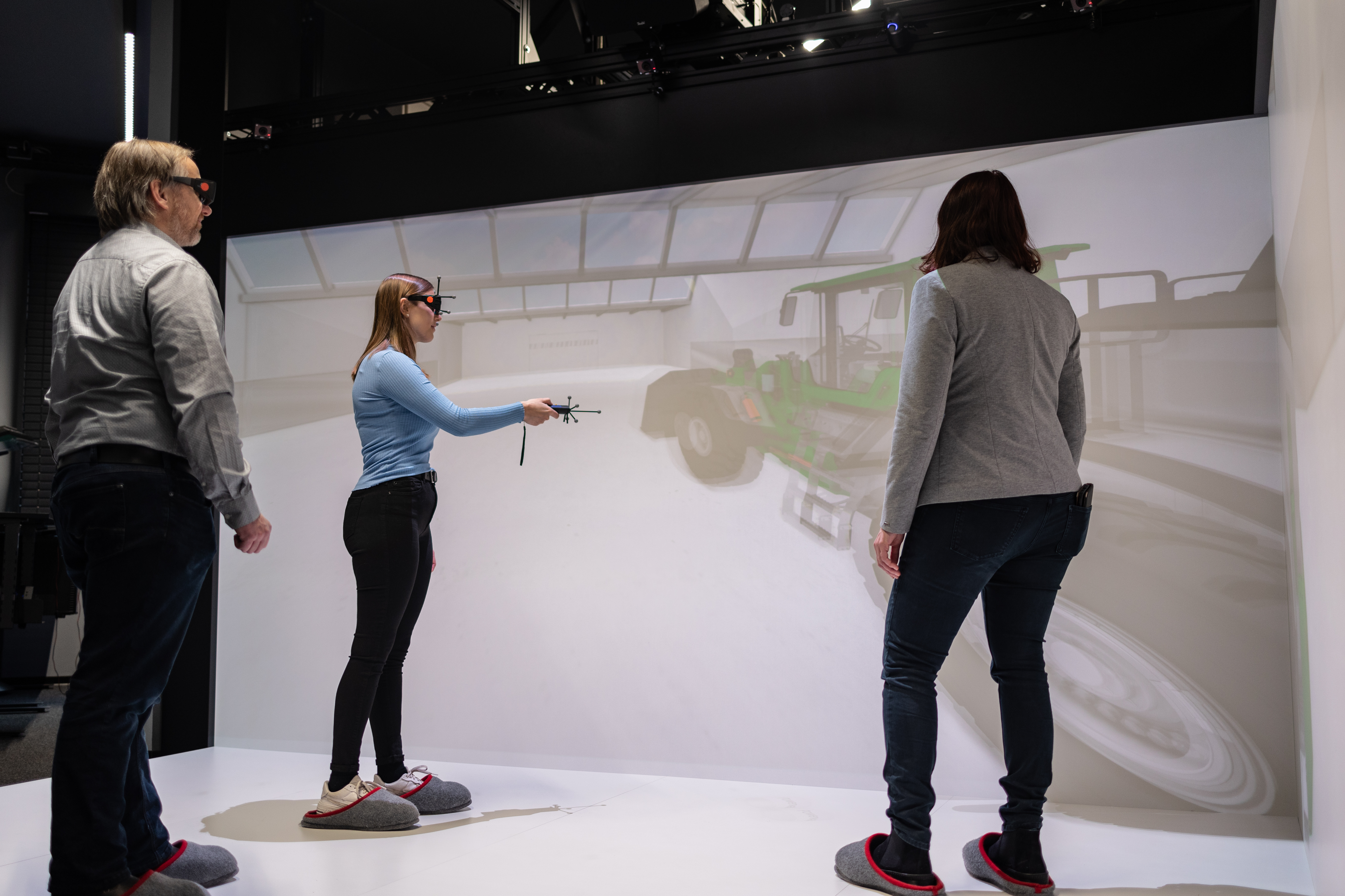 Studierende demonstriert zwei Dozierenden etwas im Virtual Reality Raum.