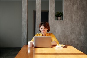Eine Frau sitzt vor einem Laptop und arbeitet konzentriert