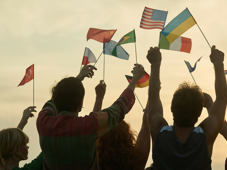 Silhouettes of people holding flags from various countries.