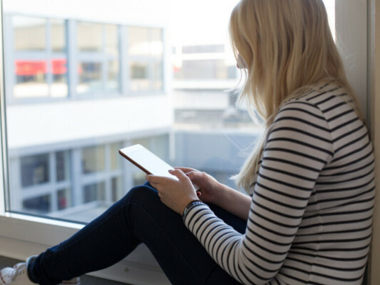 Studierende sitzt am Campus Wilhelmshaven mit Tablet an einem Fenster