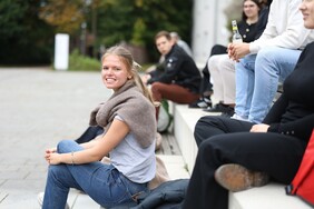 Studierende sitzen draußen auf Steinstufen