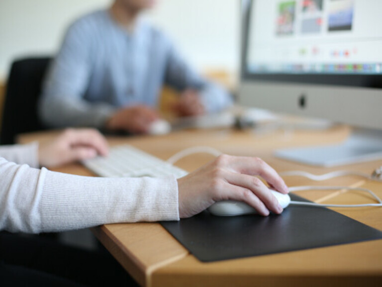 Hands using a computer mouse and keyboard