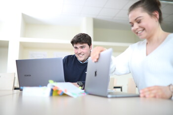 Studierende mit Laptops und Gesetzestext