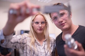 Zwei Studierende halten Flüssigkeit vor sich Zwei Studierende halten Flüssigkeit vor sich