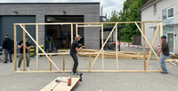 Holzrahmen wird von Studierenden getragen