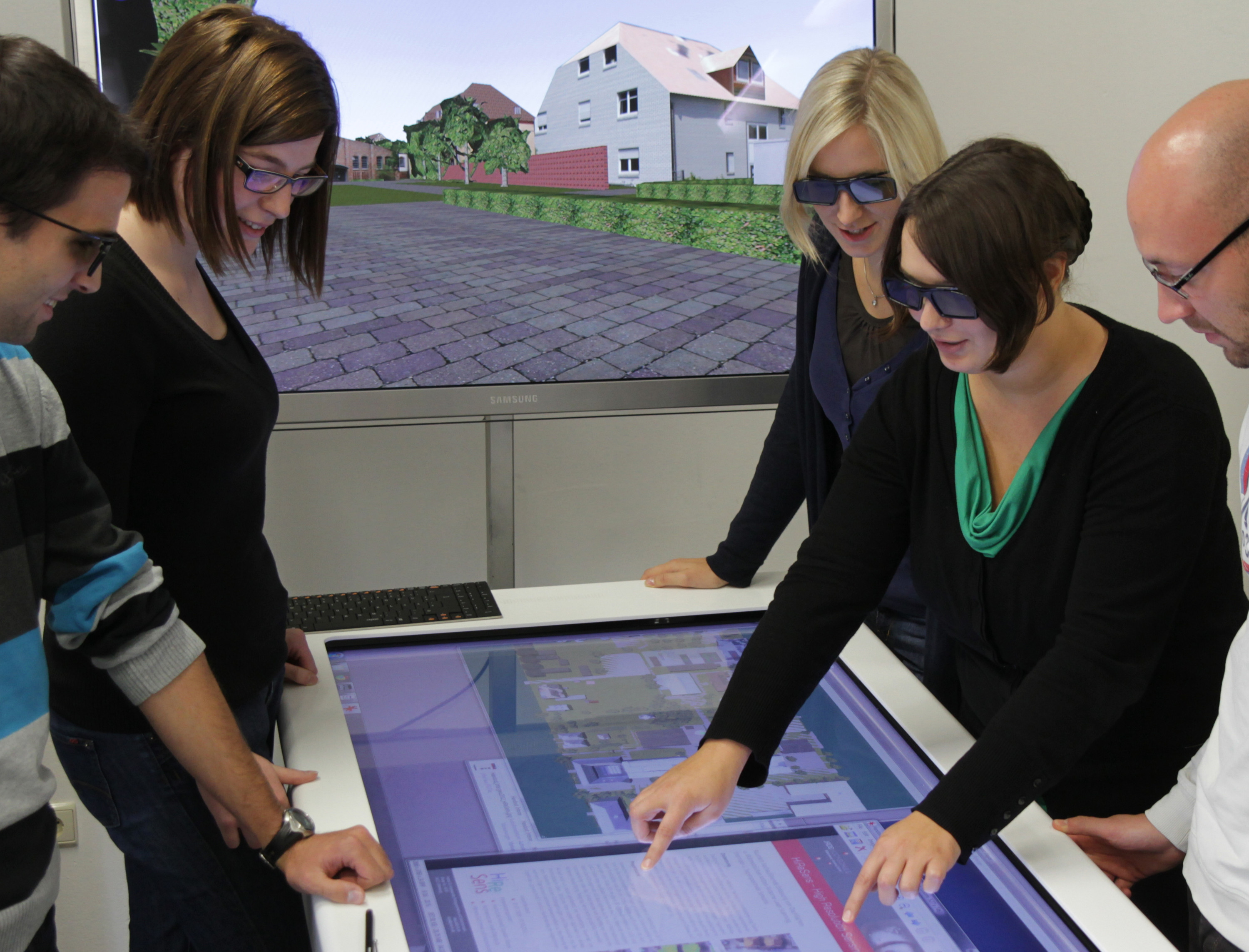 Studierende betrachten an einem Touch Table ein 3D-Stadtmodell Studierende betrachten an einem Touch Table ein 3D-Stadtmodell
