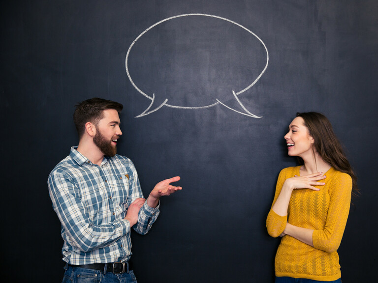 Happy couple talking over chalkboard background with drawn dialogue