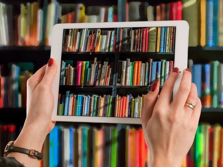 Bunte Büchersammlung durch ein Tablet betrachtet