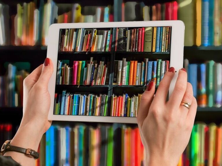 Bunte Büchersammlung durch ein Tablet betrachtet