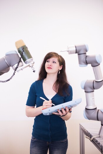 Studentin macht sich zwischen Roboterarmen Notizen Studentin macht sich zwischen Roboterarmen Notizen