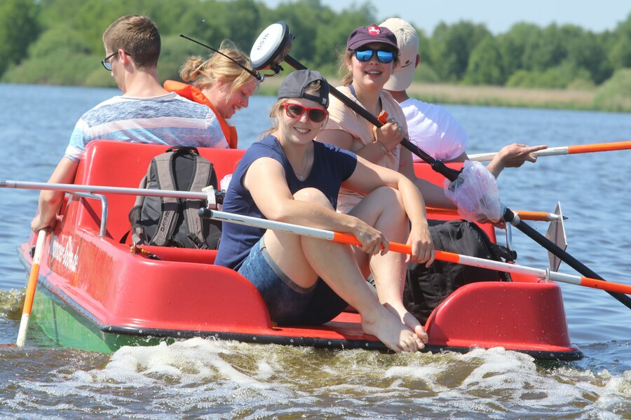 Mehrere Studierende sitzen auf einem Tretboot und haben Vermessungszubehör in der Hand