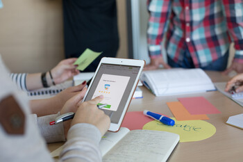 Besprechung zwischen Studierenden mit einem Tablet 