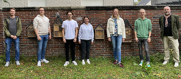 Prof. Dr.-Ing. Roland Hergert, die fünf Studierenden, sowie Julian Schünke vom Gebäudemanagement vor den Insektenhotels (v. li.): Julian Schünke, Dennis Bibow, Jonah Schmidt, Fiona Schmitz, Franziska Härtle und Sebastian Kramme, Roland Hergert
